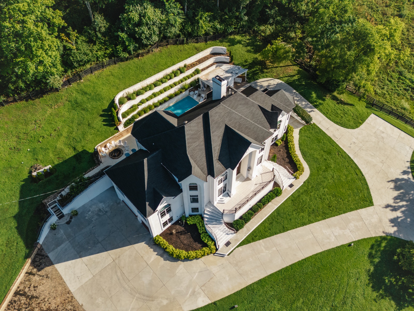 The 4.1 gated acres from above: the house, the pool terraces, and the drive down to the road.