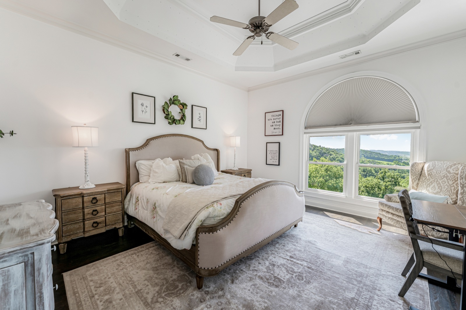 Bedroom three: cream linens under a tray ceiling, windows to the hills.