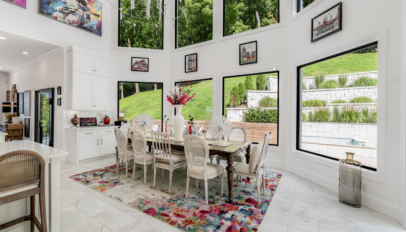 The breakfast area in morning light, ringed by two stories of windows over the lawn.