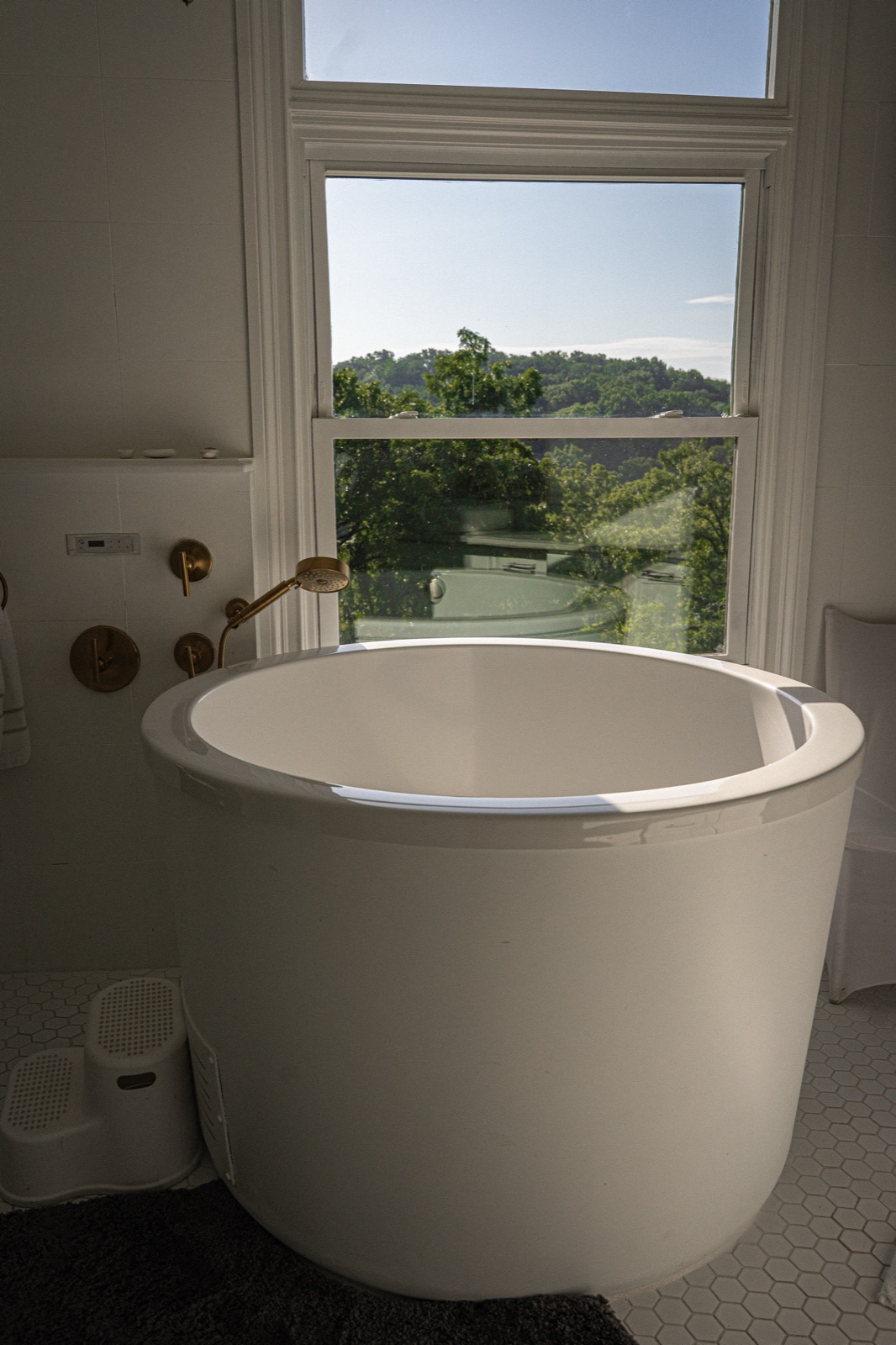 The soaking tub, brass-trimmed, at the window