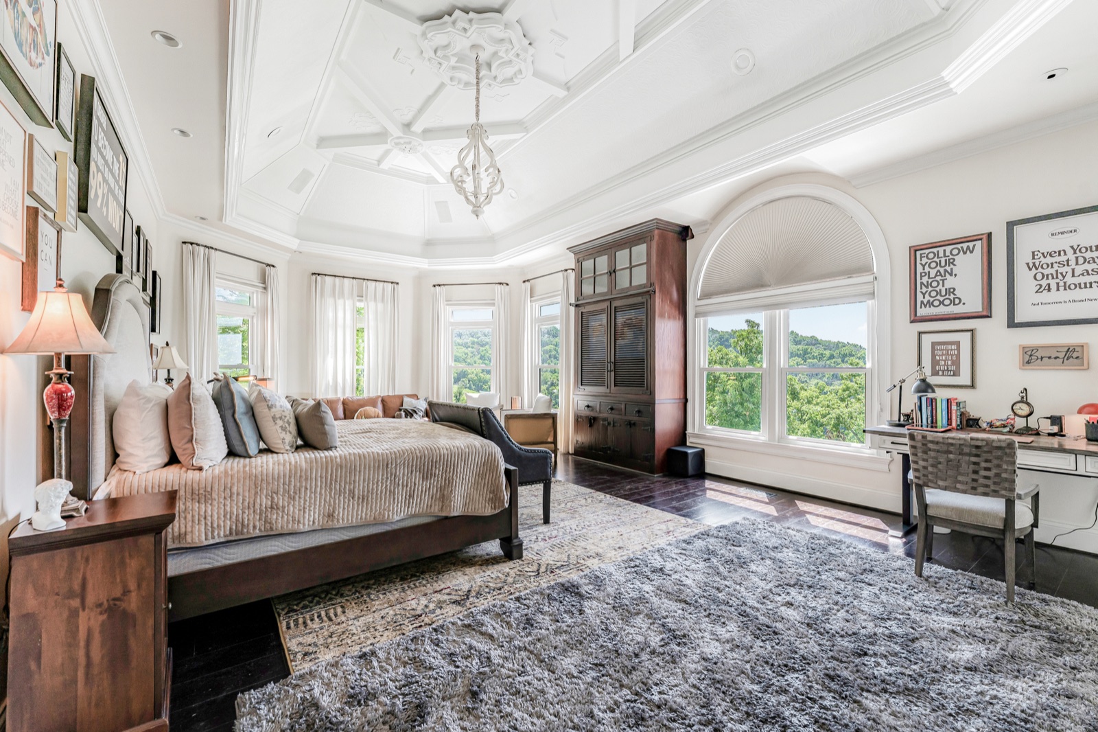 The owner's suite wide: coffered ceiling, a bay of windows over the hills, statements on the walls.