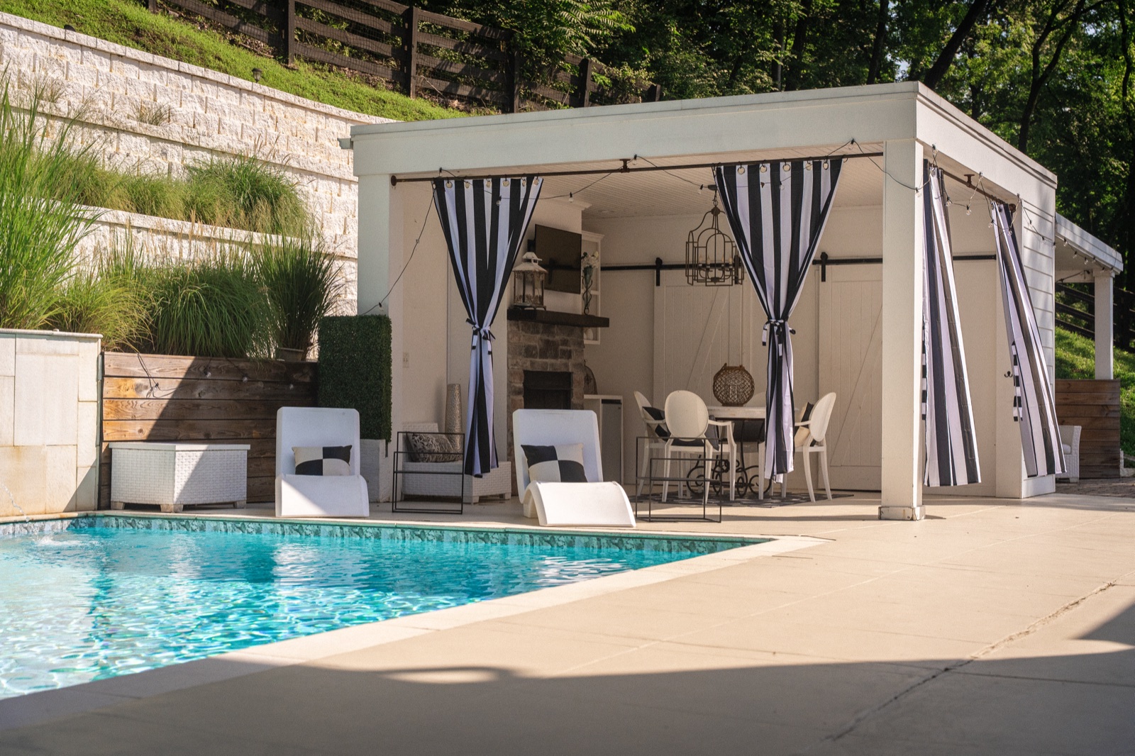 The poolside cabana, curtains drawn back, loungers at the water's edge.