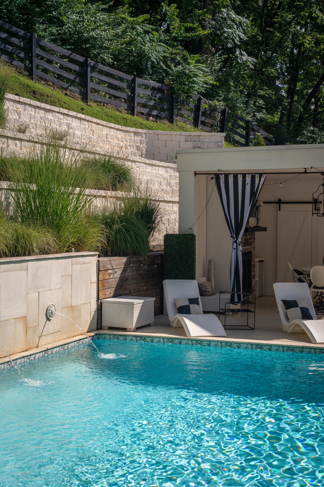 The heated pool, fountains arcing toward the curtained cabana.
